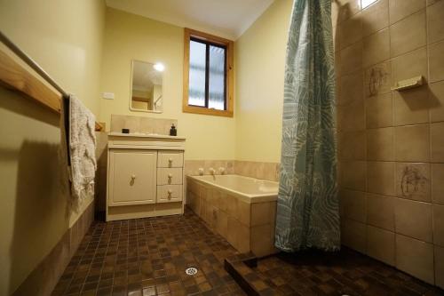 a bathroom with a tub and a sink and a shower at Karriwood Cottage in Pemberton