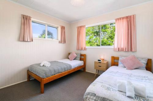 two beds in a room with two windows at Spacious Utuhina holiday House in Rotorua