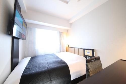 a hotel room with a bed and a flat screen tv at APA Hotel Asakusa Tawaramachi Ekimae in Tokyo