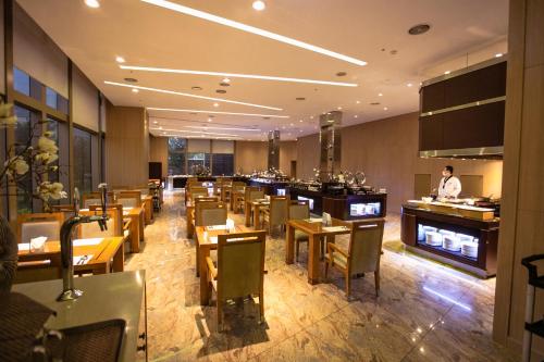 a restaurant with wooden tables and chairs and a man standing at a counter at Songdo Central Park Hotel in Incheon