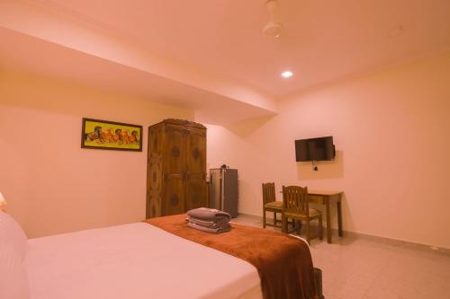 a bedroom with a bed and a table and a tv at Primavera Holiday Homes-FAMILY RUN GOAN GUEST HOUSE in Candolim