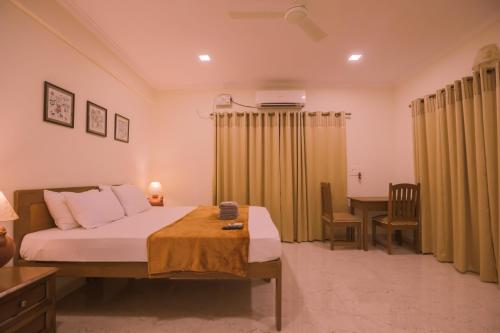 a bedroom with a bed and a desk and a table at Primavera Holiday Homes-FAMILY RUN GOAN GUEST HOUSE in Candolim
