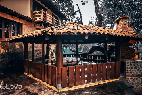 a wooden gazebo in front of a house at Cabaña DNellys Rosa con cancha de basquetbol in Mazamitla