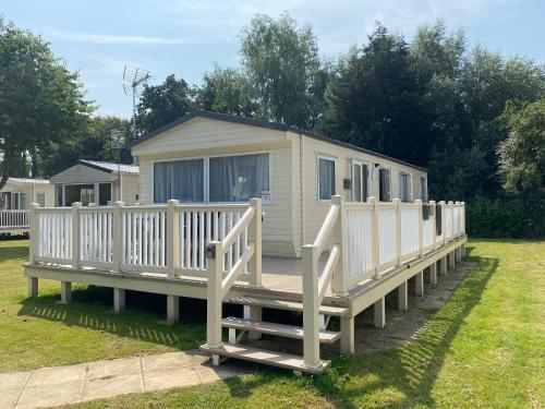 a tiny house with a porch and a fence at KellysHolidayHomes Atlas 3 bedrooms caravan in Weeley