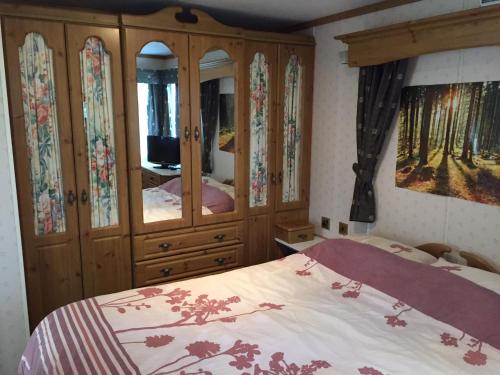 a bedroom with a bed and a large wooden cabinet at Spacious caravan with DG, CH & veranda in Skegness