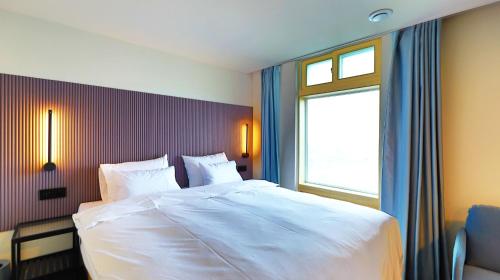 a bedroom with a large white bed with a window at Little Prince Hotel&Condo in Gunsan