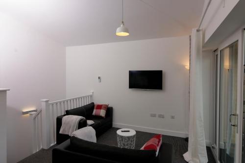a living room with a couch and a tv on a wall at Canal View Apartment in Bletchley