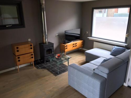 uma sala de estar com um sofá e uma lareira em Leuk vakantiewoning dijk woning met 3 slaapkamers dicht bij de Belgische grensen em Westdorpe