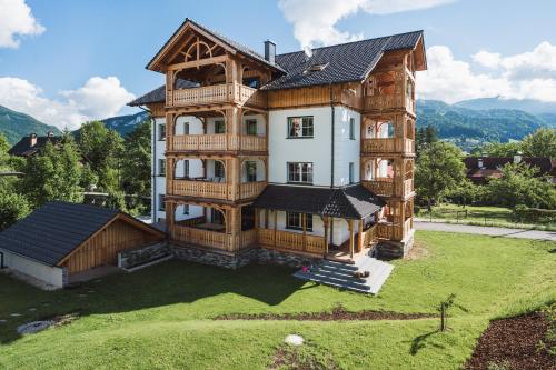 ein großes Holzhaus mit Balkon auf einem Hof in der Unterkunft Ferienwohnungen Villa Salzweg in Bad Goisern