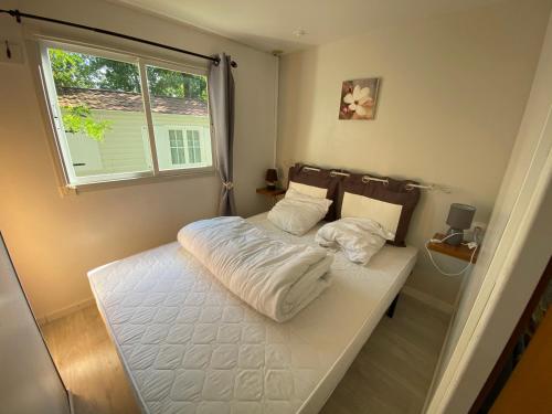 ein kleines Schlafzimmer mit einem weißen Bett und einem Fenster in der Unterkunft Mobile Home Zen pour 4 à 6 pers camping 4* Saint Paul Les Dax in Saint-Paul-lès-Dax