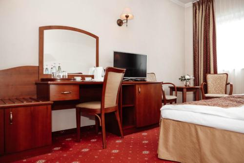 a hotel room with a desk and a mirror at Hotel Sympozjum & SPA in Kraków