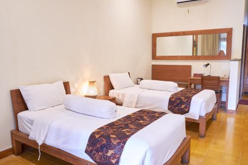 a room with three beds and a mirror at Rumah Mertua Heritage in Yogyakarta