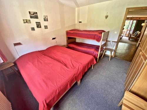 two beds in a room with red sheets at 4 person apartment in central location in Morgins