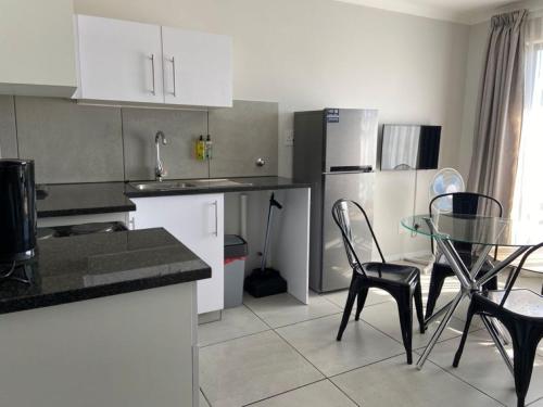 a kitchen with white cabinets and a glass table and chairs at MINT Express Sandton View in Johannesburg