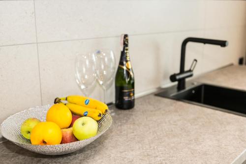 a bowl of fruit on a counter with a bottle of wine at Пентхауз с террасой район Мост Сити in Dnipro