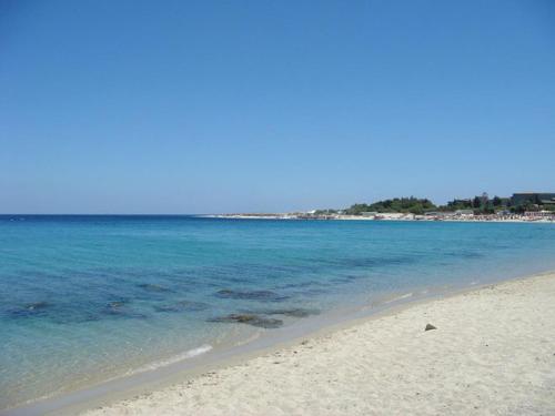 a sandy beach with the ocean and the blue water at La Maison Du Parc in SantʼAndrea Apostolo dello Ionio