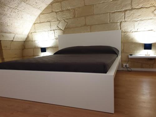 a white bed in a room with a stone wall at 29BARRA31 in Merine