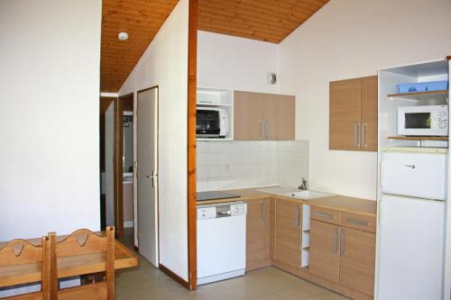 a kitchen with white appliances and wooden cabinets at Résidence Azureva La Clusaz les Aravis in La Clusaz