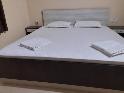 a bed with white sheets and towels on it at Raaj Inn studio's in Candolim