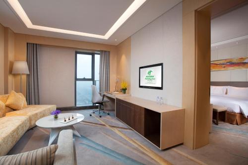 a hotel room with a bed and a living room at Holiday Inn Suzhou Huirong Plaza, an IHG Hotel in Suzhou