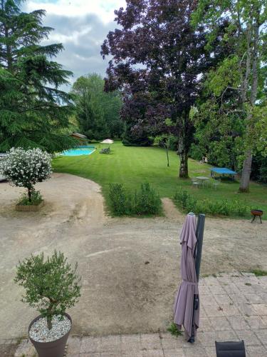 a garden with an umbrella and a swimming pool at le domaine du chaffard in Les Avenières