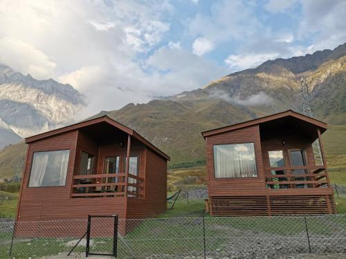 a couple of houses with mountains in the background at Kazbegi Twins in Kazbegi