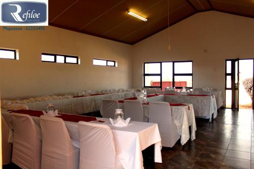 un comedor con mesas blancas y sillas blancas en Refiloe Guesthouse, en Leribe