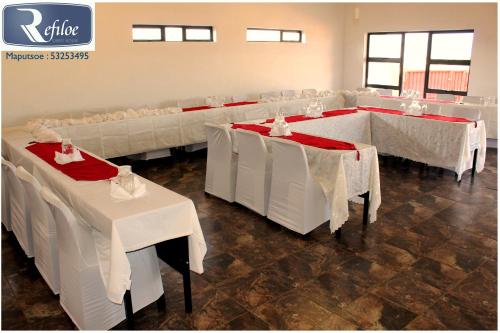 un comedor con mesas blancas y sillas blancas en Refiloe Guesthouse, en Leribe