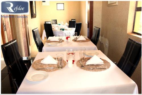 un conjunto de mesas con manteles y anteojos blancos en Refiloe Guesthouse, en Leribe