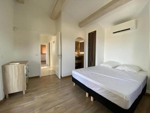 - une chambre avec un grand lit blanc et un couloir dans l'établissement villa beaupré, aux Issambres