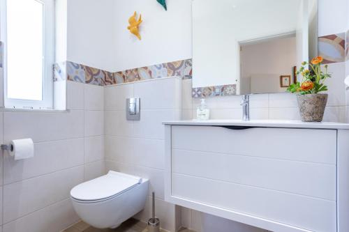 een witte badkamer met een toilet en een wastafel bij Paraíso dos Pássaros in Budens