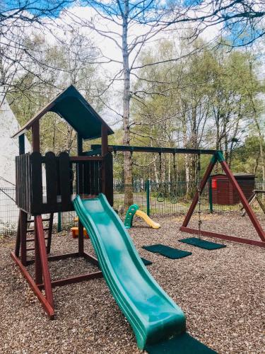 a playground with a slide and a swing set at Corralea Cottages in Belcoo