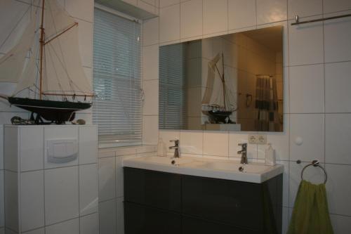 baño con lavabo y un velero en un espejo en Landhaus an der Wiek, en Poseritz