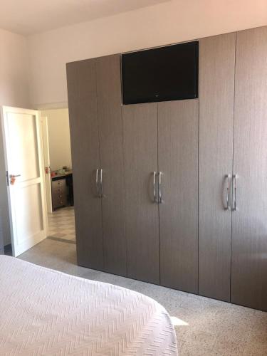 1 dormitorio con armarios de madera y TV de pantalla plana en Casa Vico Torre, en Santa Croce di Magliano