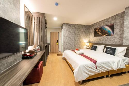 a hotel room with a large bed and a television at Metro Hotel Ratchada 36 in Bangkok