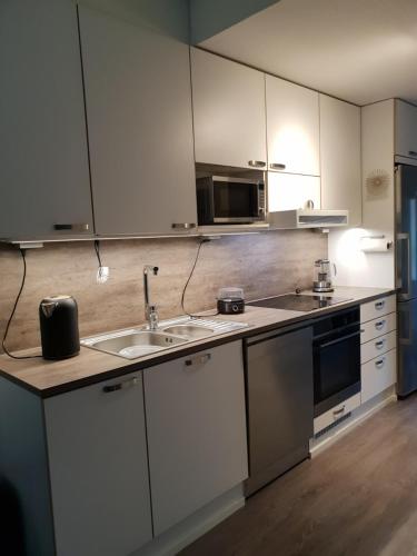 a kitchen with white cabinets and a sink and a microwave at J House in Jyväskylä