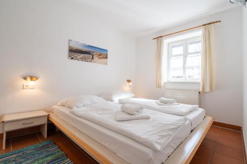 ein weißes Bett in einem Zimmer mit Fenster in der Unterkunft Feriendorf Rugana - Komfort Appartement mit 1 Schlafzimmern und Terrasse C39 in Dranske