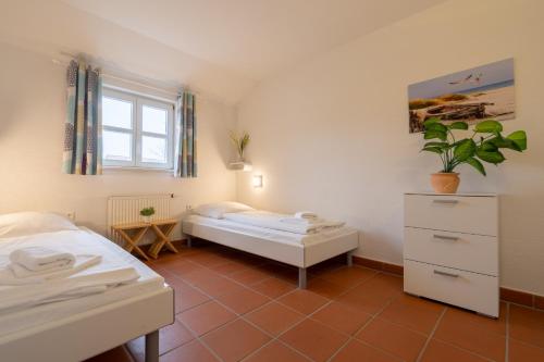 a bedroom with two beds and a window at Feriendorf Rugana - Klassik Appartement mit 2 Schlafzimmern und Terrasse C27 in Dranske
