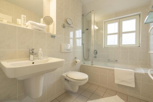 a bathroom with a sink and a toilet and a shower at Feriendorf Rugana - Klassik Appartement mit 2 Schlafzimmern und Terrasse C27 in Dranske