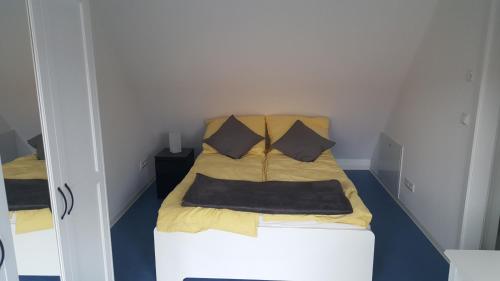 um pequeno quarto com uma cama com lençóis e almofadas amarelas em Ferienwohnung auf dem Bauernhof em Grossräschen