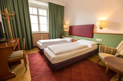 a hotel room with two beds and a table at Classic Hotel Am Stetteneck in Ortisei