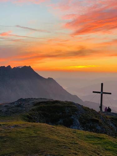 a cross on top of a hill with a sunset at Bergkristallhaus in Ramsau am Dachstein