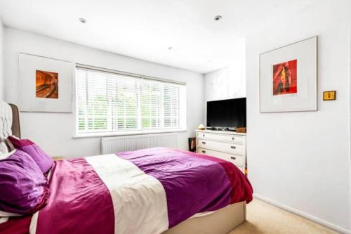 a bedroom with a bed and a dresser and a window at Luxurious 4 bed house with private garden in Saint Mary Cray