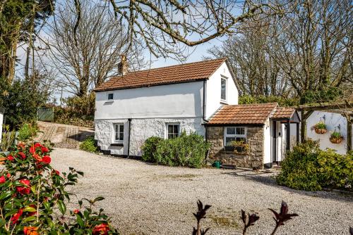 a small white house with a red roof at Tresowes Green Cottage in Helston