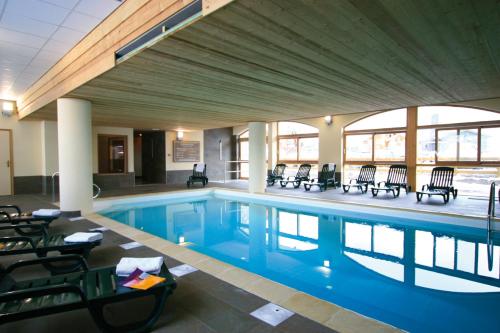 a large swimming pool with chairs in a building at travelski home select - Résidence L'Ecrin des Sybelles in La Toussuire