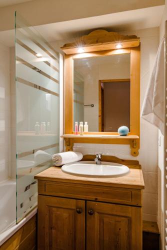 une salle de bain avec un lavabo, un miroir et une baignoire dans l'établissement travelski home select - Résidence L'Ecrin des Sybelles, à La Toussuire