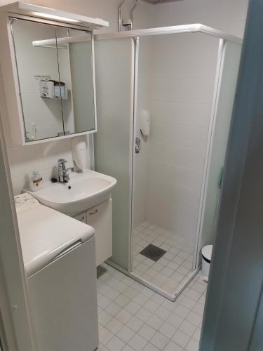 a white bathroom with a shower and a sink at Ylläs Kanerva 102 in Äkäslompolo