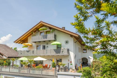 a house with a balcony with tables and umbrellas at Wander und Aktiv Hotel Rösslwirt in Lam