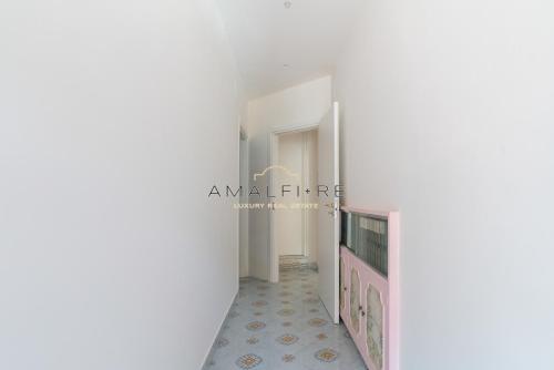a corridor of a house with white walls and tile floors at Casa Smeraldo in Amalfi