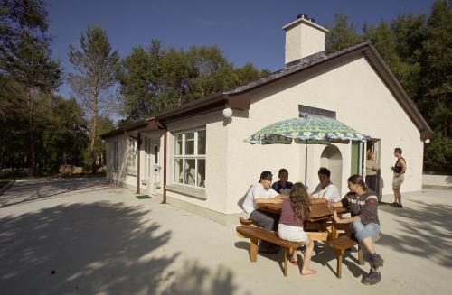 a group of people sitting at a table under an umbrella at Corralea Cottages in Belcoo